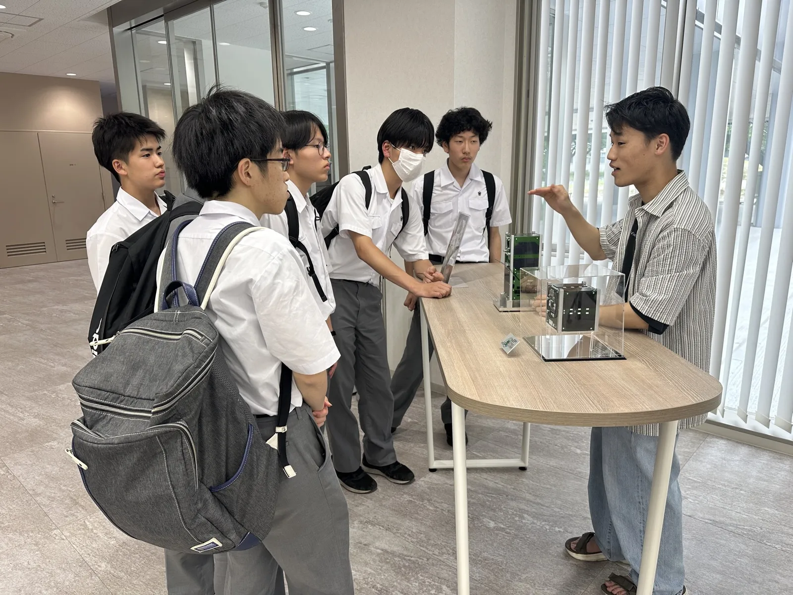 缶サット実物を見学しながらスタッフの説明を聞く生徒たち