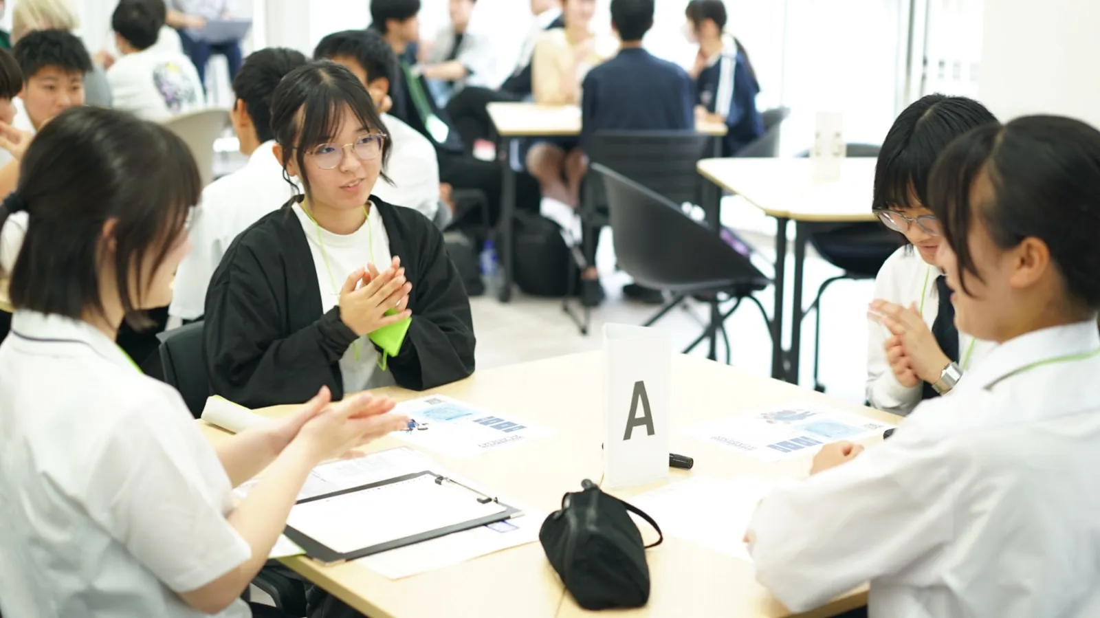 チームAの机を囲んで身振り手振りで話し合う高校生たち