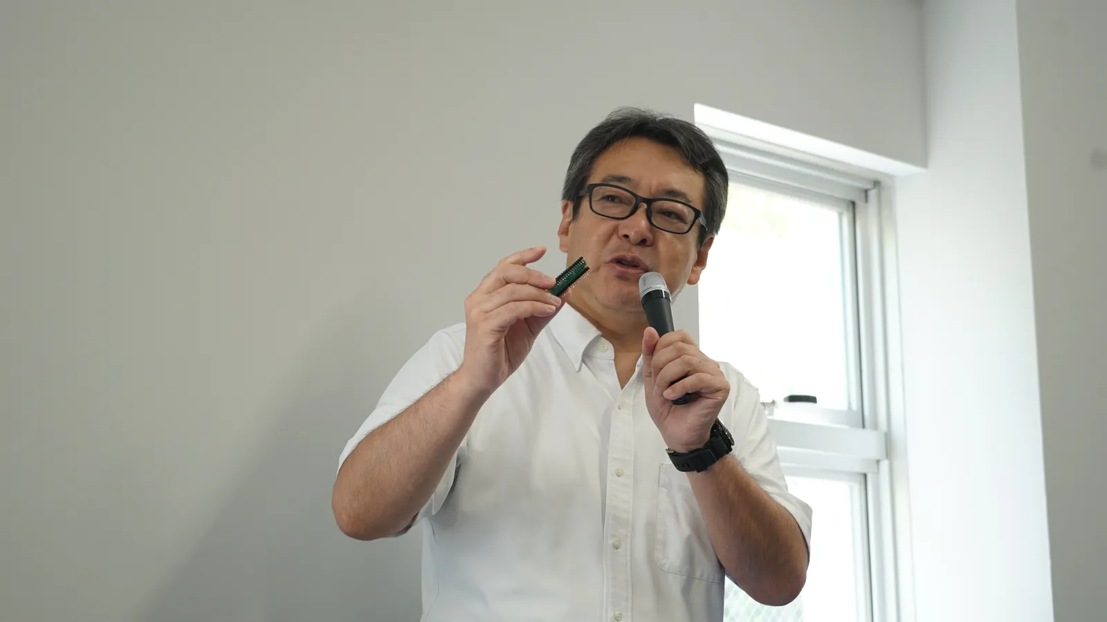 Raspberry Pi Pico を手に持ち、マイコンのしくみを説明する前田恵介先生