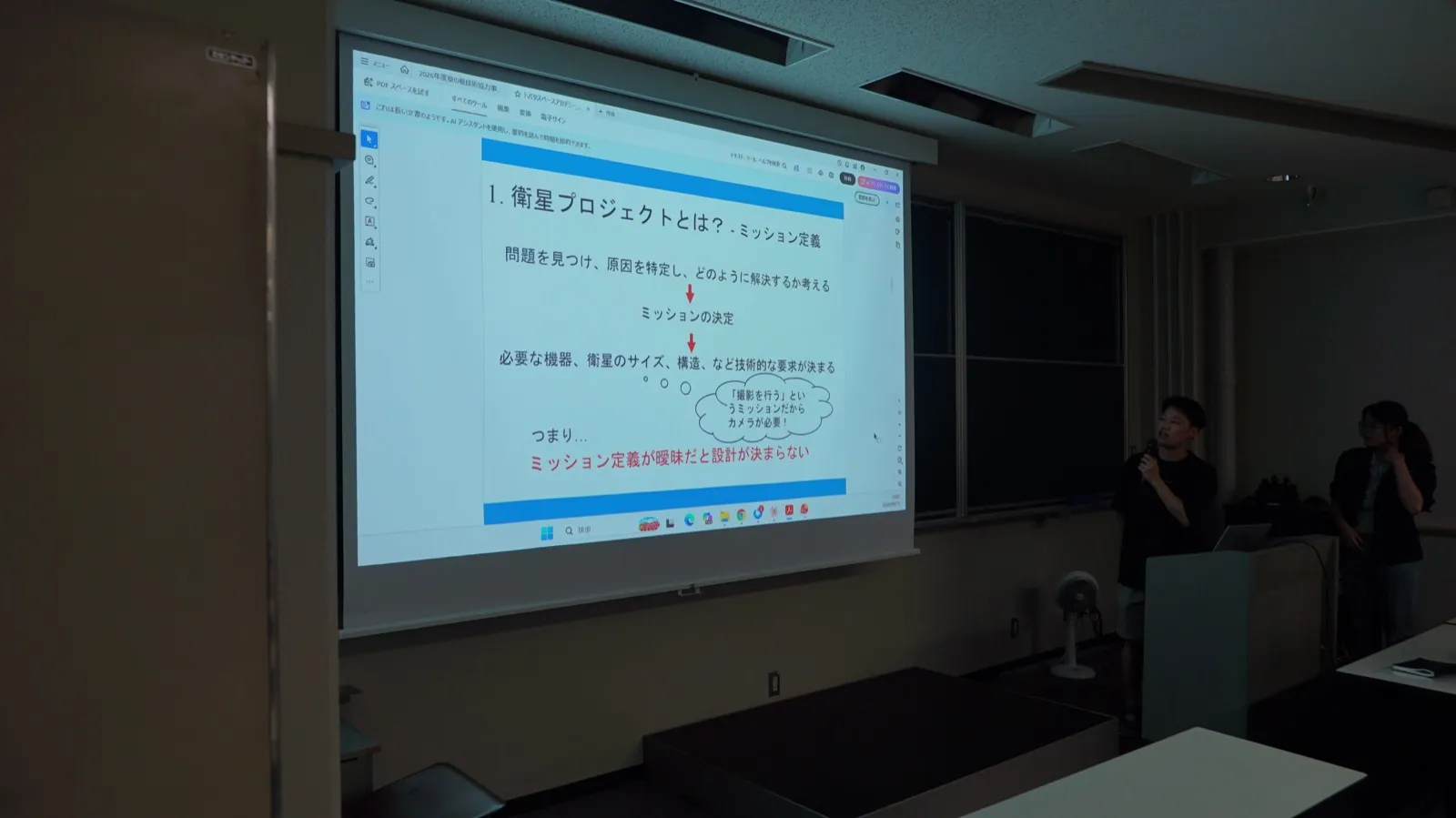 「ミッション定義」のスライドを映しながら説明する学生たち