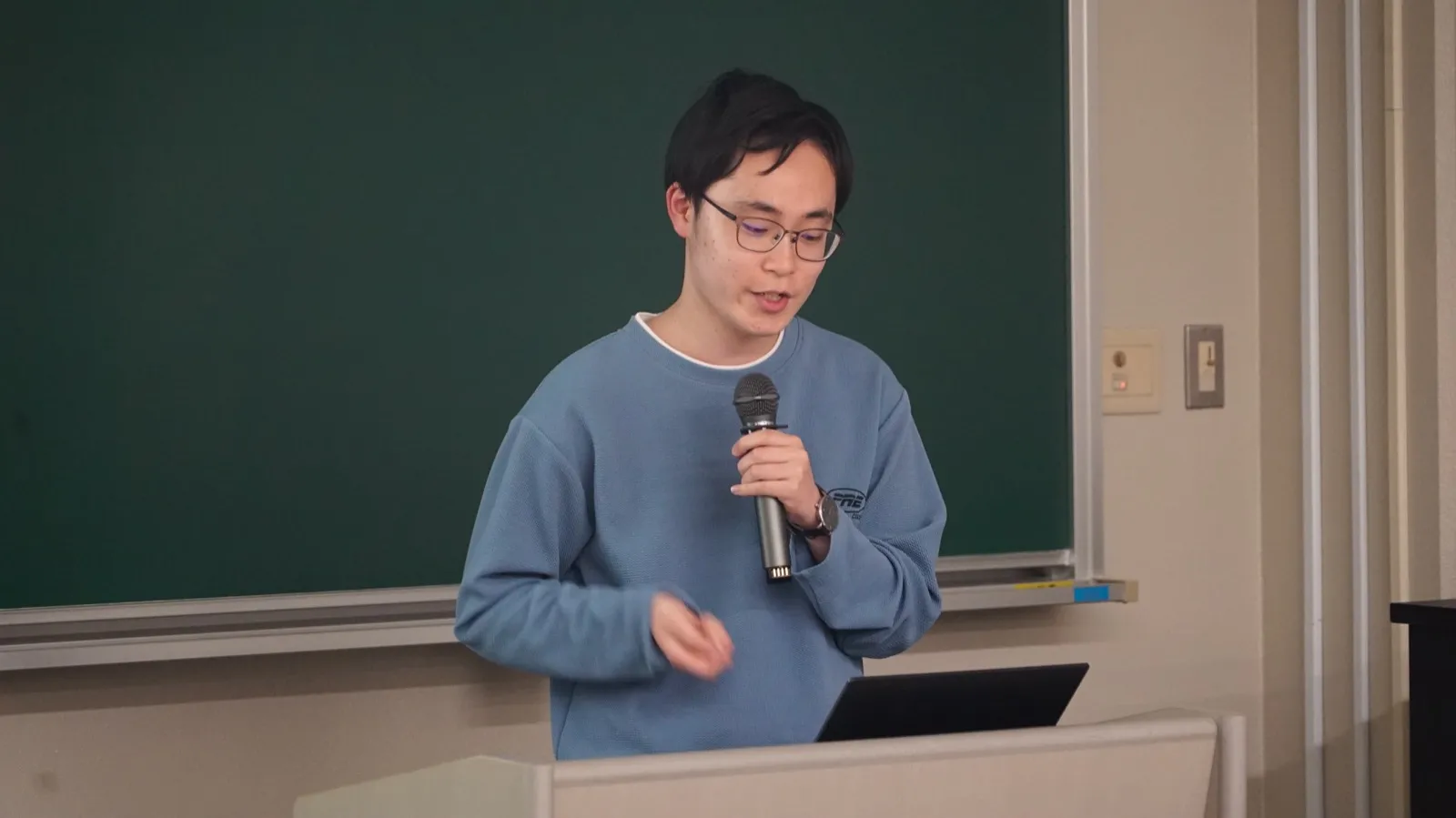 マイクを持ち、回路設計について説明する九州工業大学の大学院生