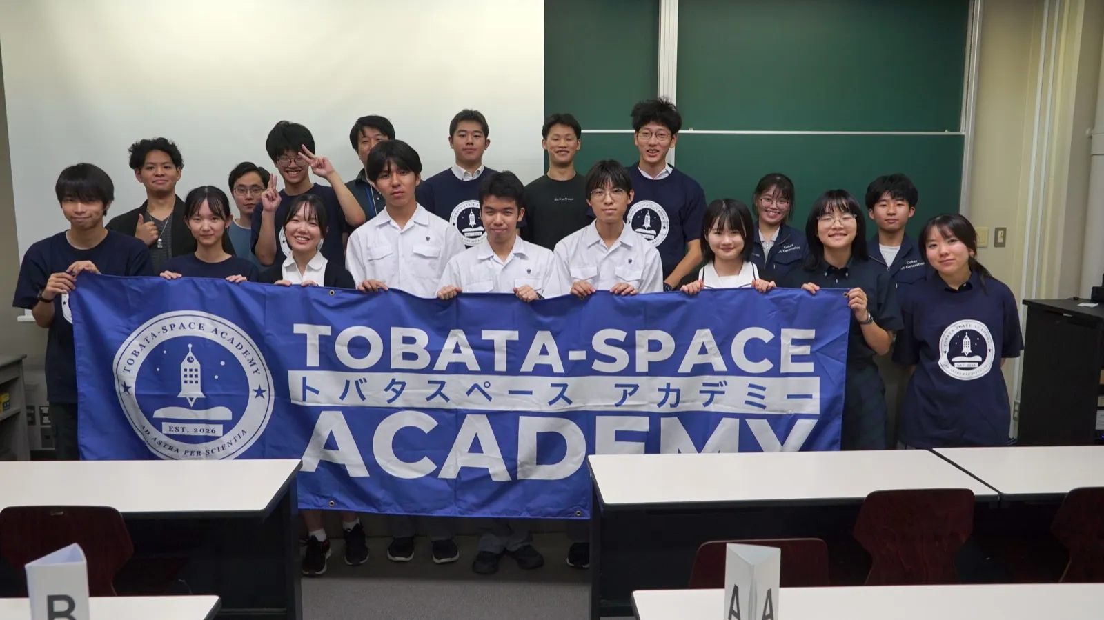 TOBATA-SPACE ACADEMY の横断幕を広げて並ぶアカデミー生と九州工業大学の学生の集合写真