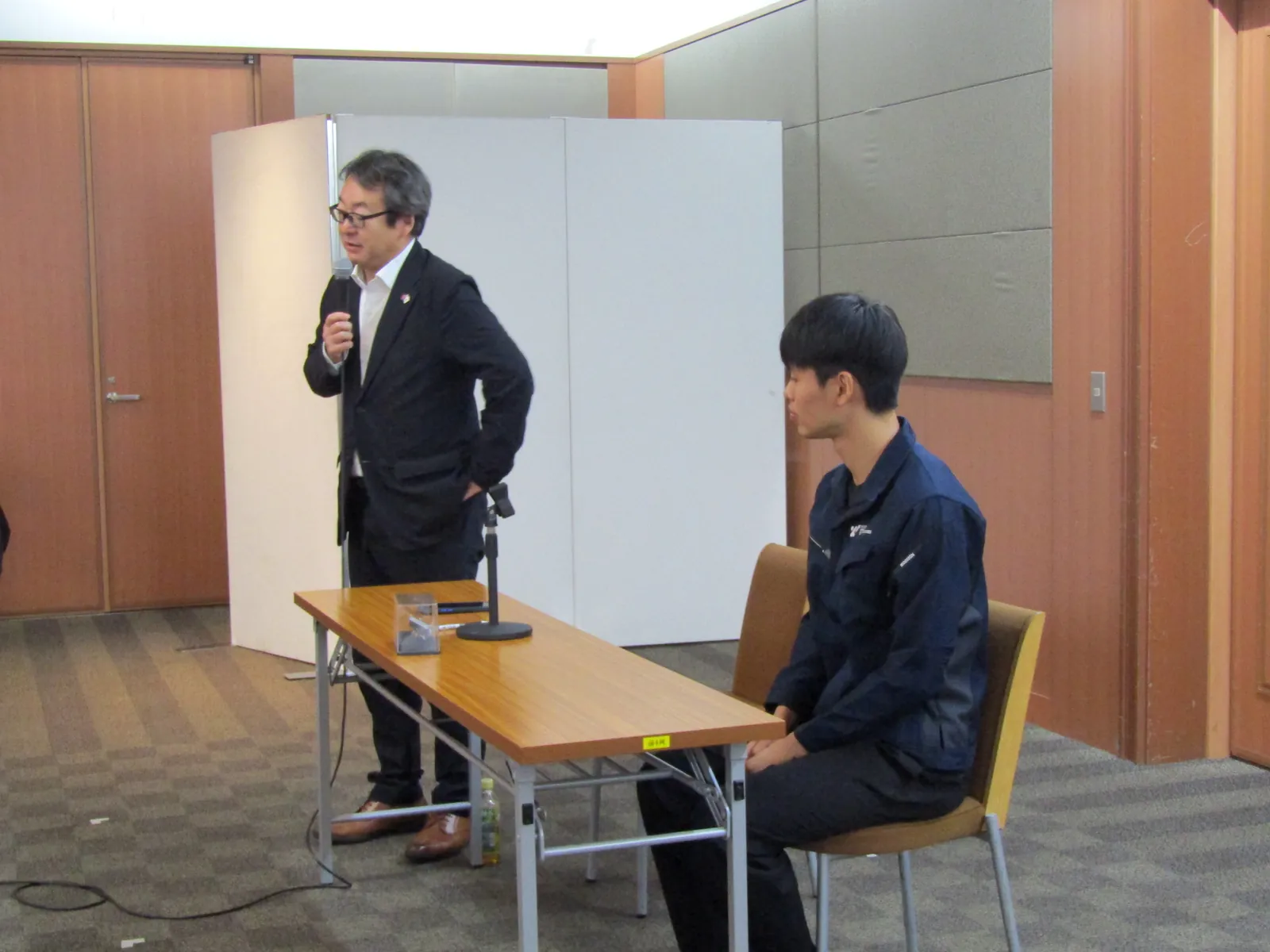審査員席からマイクを持って講評する審査員
